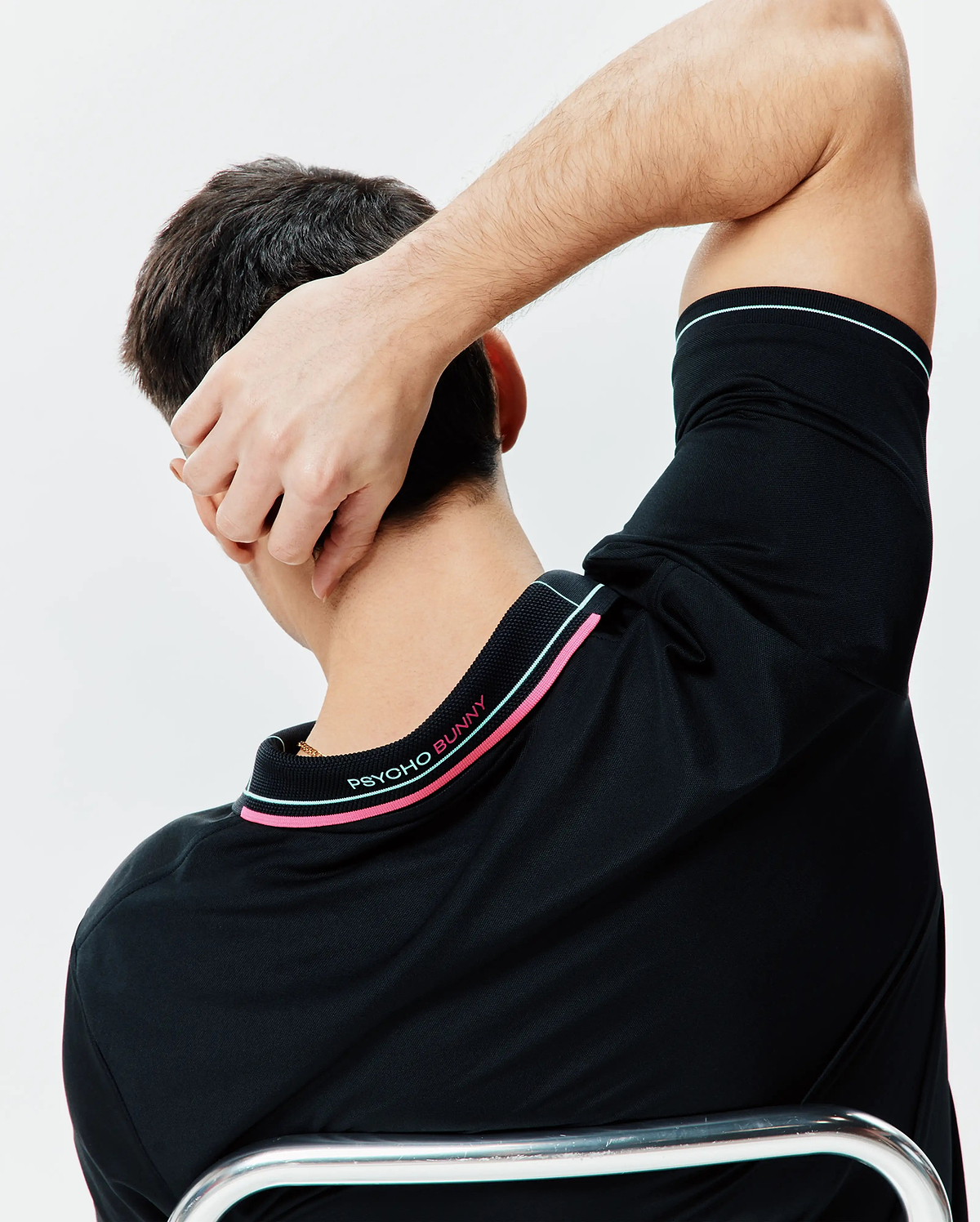 Black Mens Edwin Sport Polo, classic fit performance jersey, with pink and light blue striped ribbed collar and sleeve cuffs, featuring embroidered PSYCHO BUNNY text on the back collar.