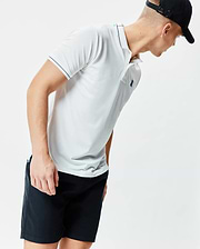 Mens Edwin Sport Polo, a white classic fit performance knit polo with black tipping on the collar and sleeves, a light blue inner collar stripe, and a small embroidered teal Psycho Bunny skull logo on the left chest.