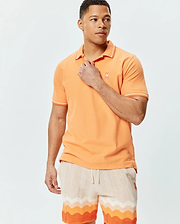 Mens Holden Pique Polo, vibrant orange pique knit, classic fit, with white striped collar and cuffs, featuring a small embroidered Psycho Bunny skull logo.