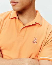 Mens Holden Pique Polo in vibrant orange, featuring a classic fit, pique knit texture, white tipped ribbed collar and cuffs, and an embroidered Psycho Bunny skull logo on the left chest.