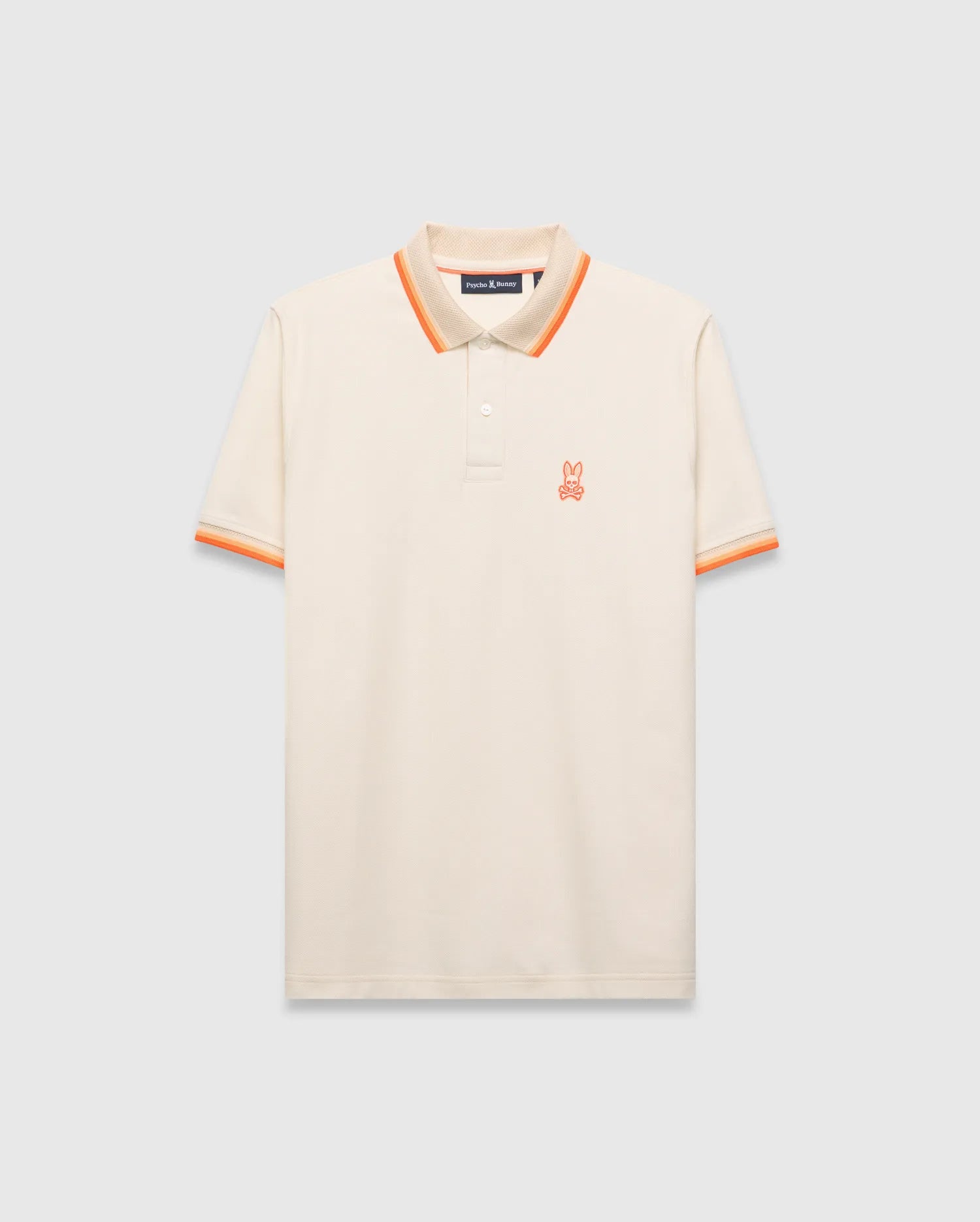 Mens Holden Pique Polo, cream classic fit with textured pique fabric, featuring an orange embroidered Psycho Bunny skull logo on the left chest, and ribbed collar/cuffs with orange and beige stripes.
