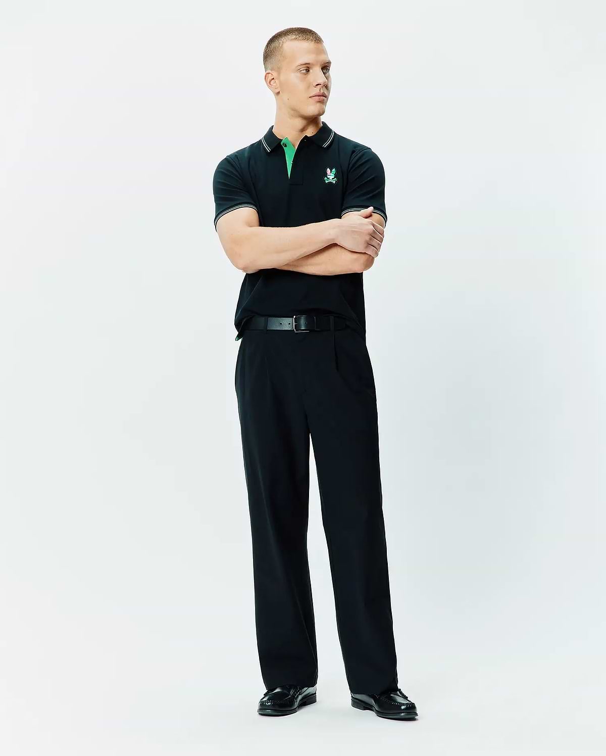 Mens Nate Pique Polo, a classic fit black pique polo shirt with a vibrant green collar, white tipping on the collar and sleeves, and an embroidered Psycho Bunny skull logo on the left chest.