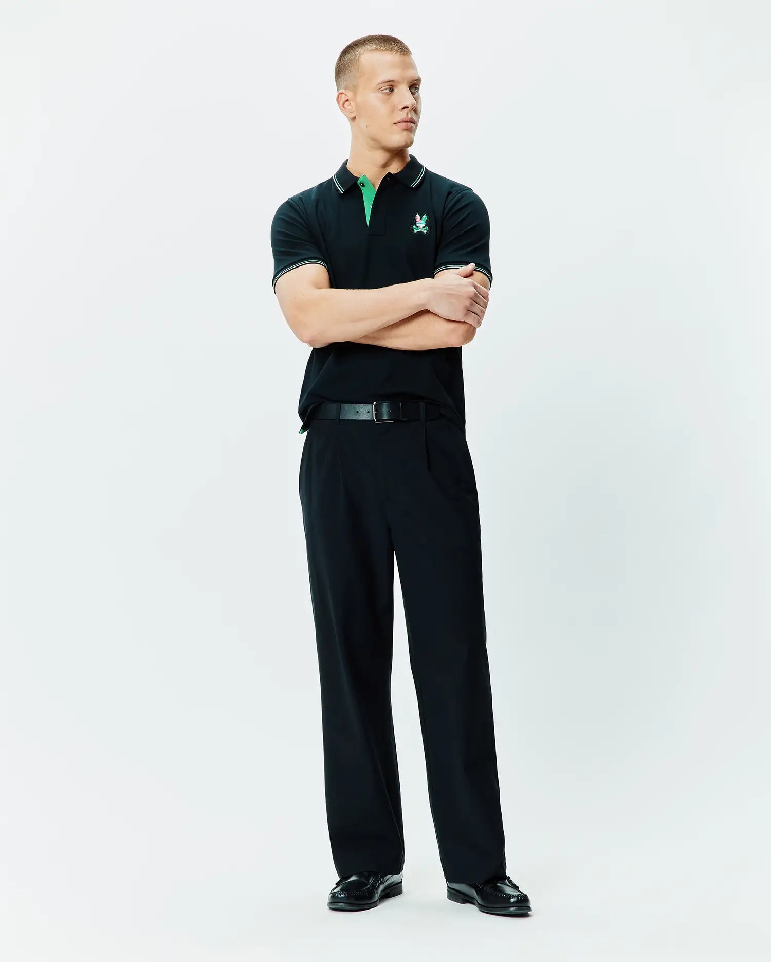 Mens Nate Pique Polo, a classic fit black pique polo shirt with a vibrant green collar, white tipping on the collar and sleeves, and an embroidered Psycho Bunny skull logo on the left chest.