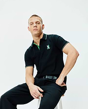 Black Mens Nate Pique Polo, classic fit pique knit, featuring a vibrant embroidered Psycho Bunny logo on the left chest, with green undercollar and white/green tipped ribbed collar and cuffs.