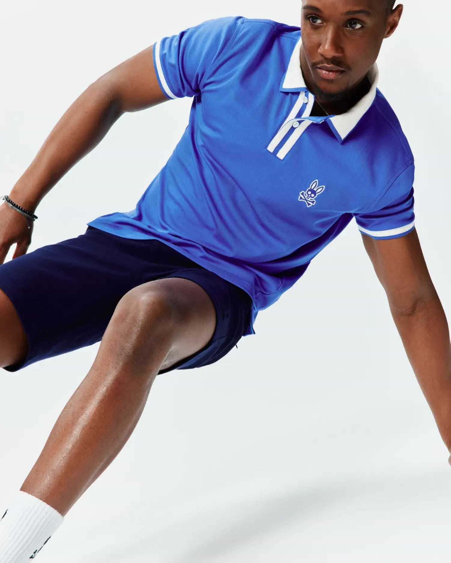 Mens Ridley Pique Polo in royal blue pique fabric, featuring a classic fit, white collar, white striped placket, white striped sleeve cuffs, and an embroidered white Psycho Bunny skull logo on the left chest.