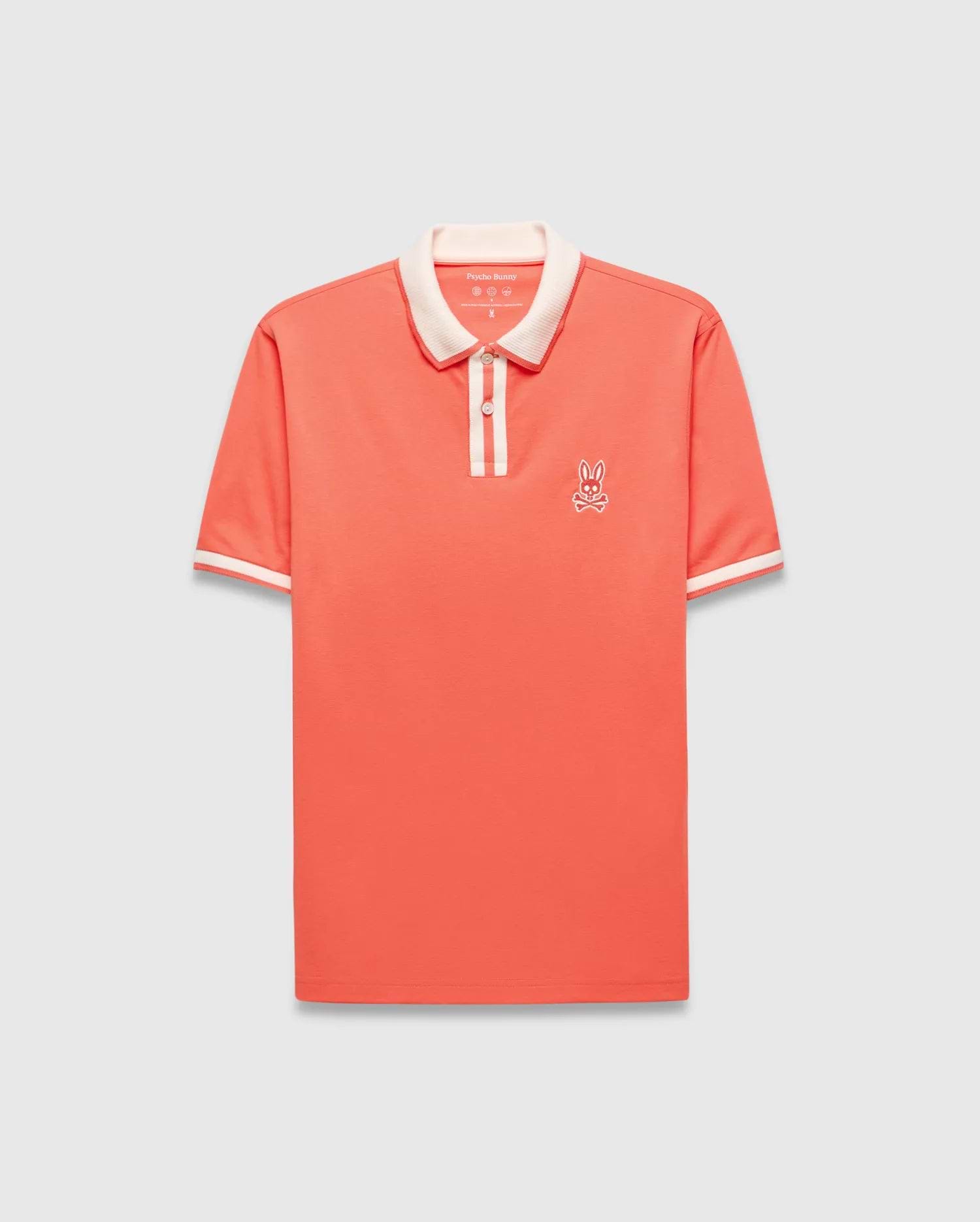 Mens Ridley Pique Polo in coral pique, featuring a classic fit, cream ribbed collar and cuffs with stripes, a two-button placket with cream stripe, and an embroidered white Psycho Bunny skull logo on the left chest.