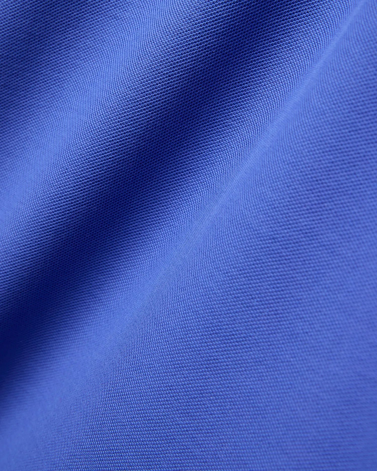 Close-up of the Mens Brad Pique Polo, featuring its vibrant royal blue color and classic textured pique knit fabric with soft, flowing folds. (5)