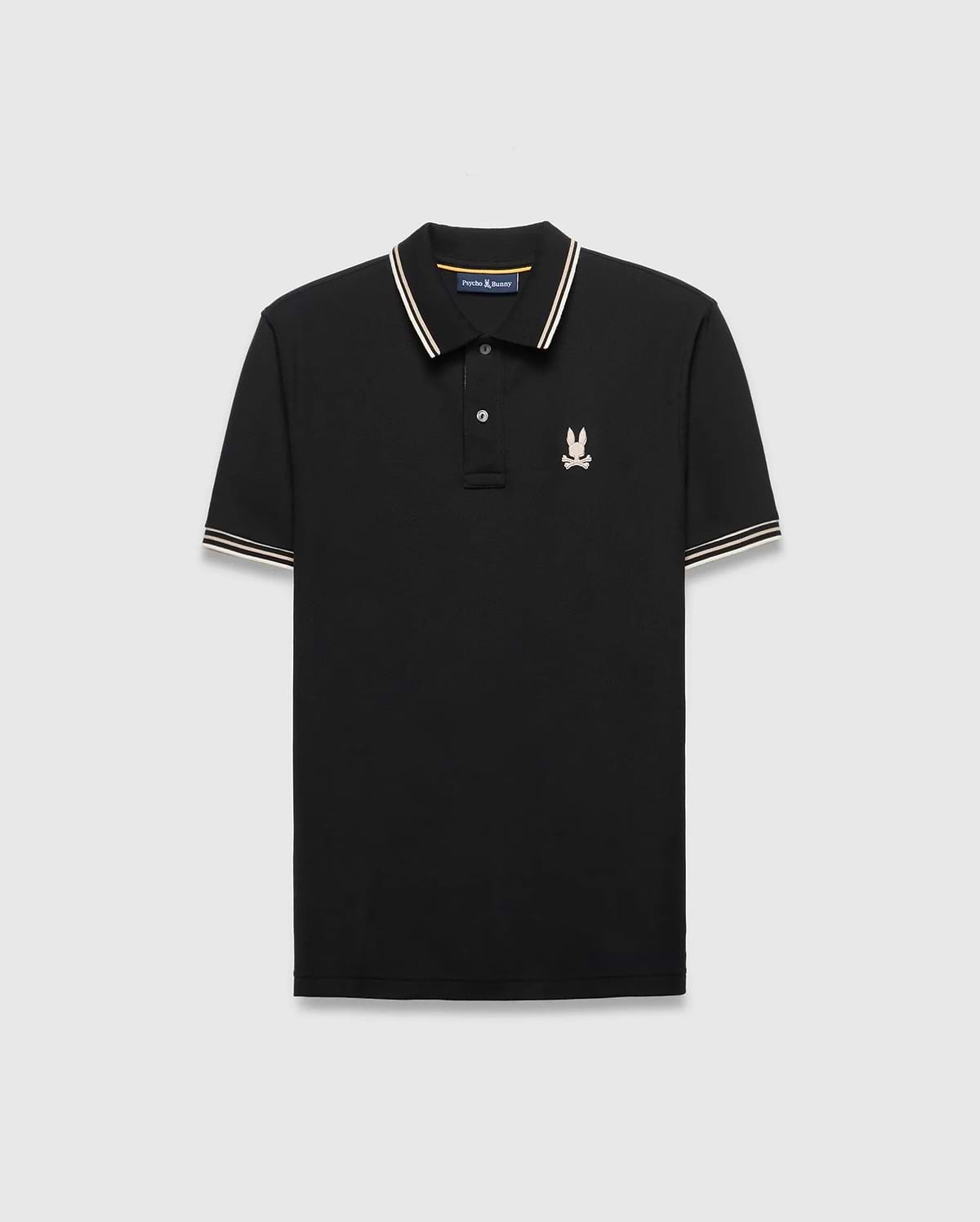 Mens Brad Pique Polo, black classic fit with white and gold striped collar and cuffs, featuring a small embroidered light pink/cream Psycho Bunny skull logo on the left chest.