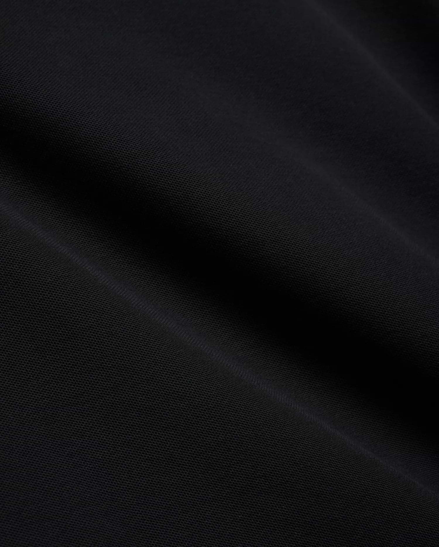 Mens Brad Pique Polo, a premium black pique knit fabric with a subtle, textured weave, showcasing the refined quality and classic style of Psycho Bunny menswear.
