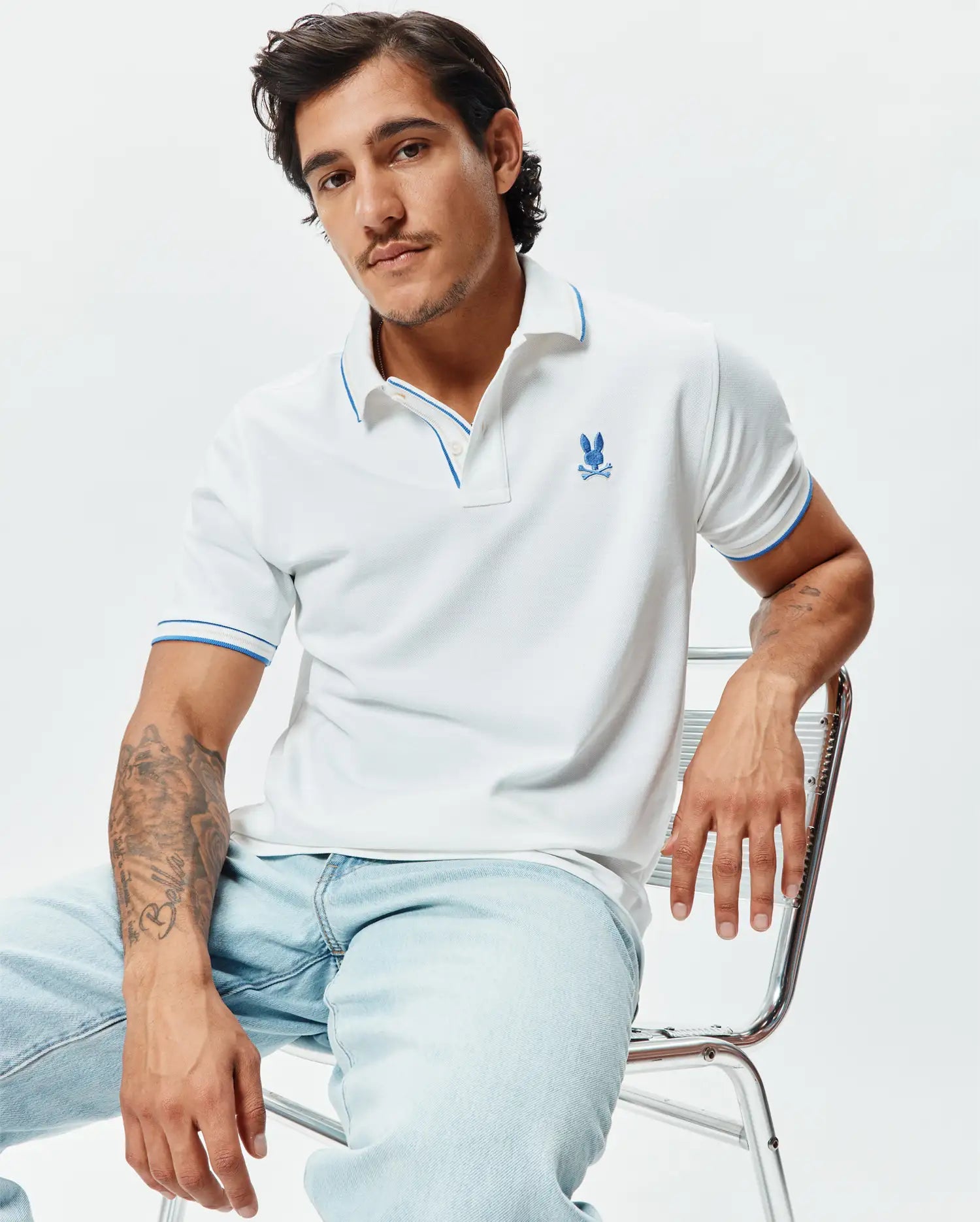 Mens Brad Pique Polo, white pique knit with blue trim on collar and sleeve cuffs, featuring an embroidered blue Psycho Bunny skull logo on the left chest, classic fit. (3)