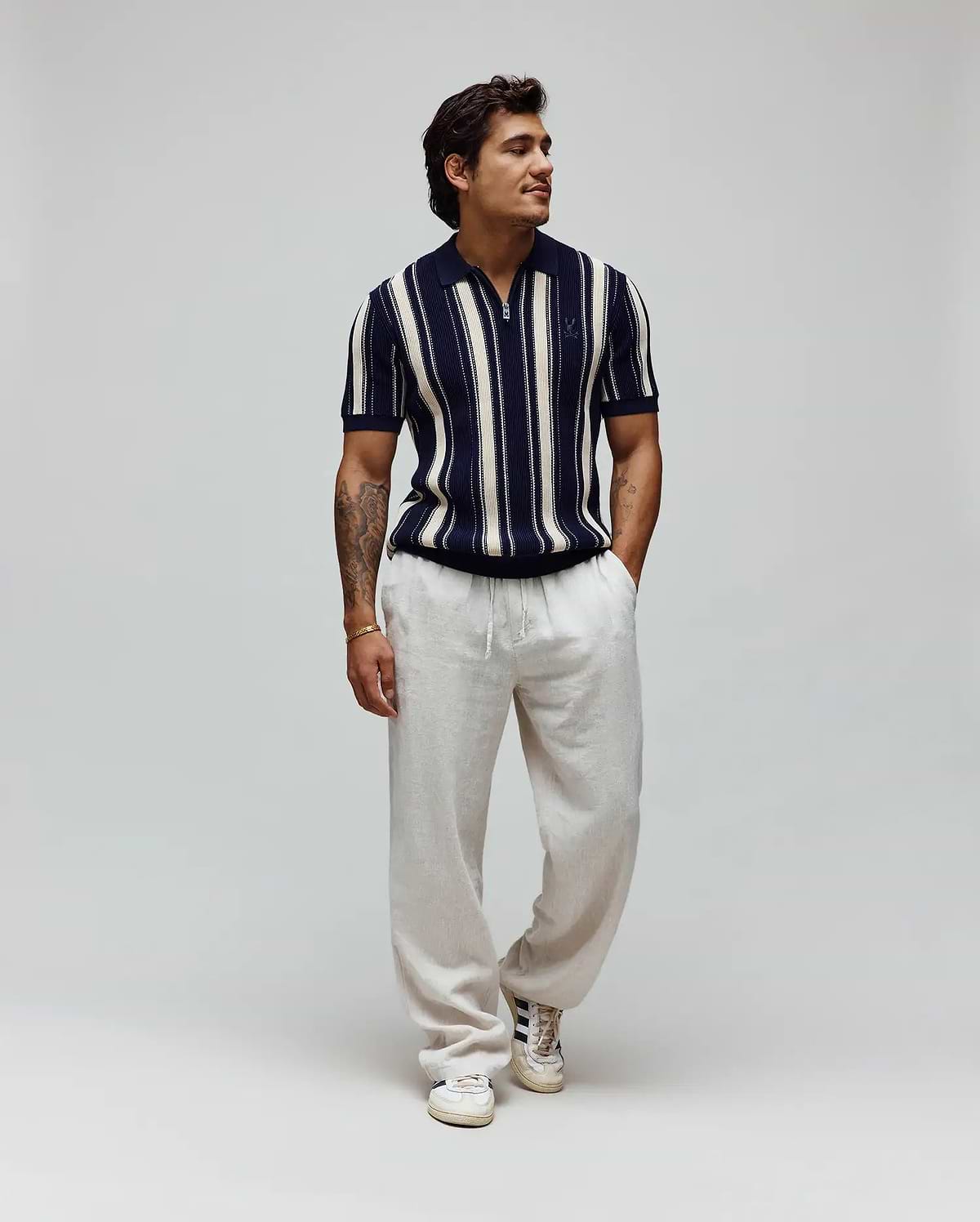 Mens Cliff Knit Zip Polo, a classic fit navy and cream vertical striped textured knit polo with a half-zip and embroidered Psycho Bunny skull logo on the left chest. (3)