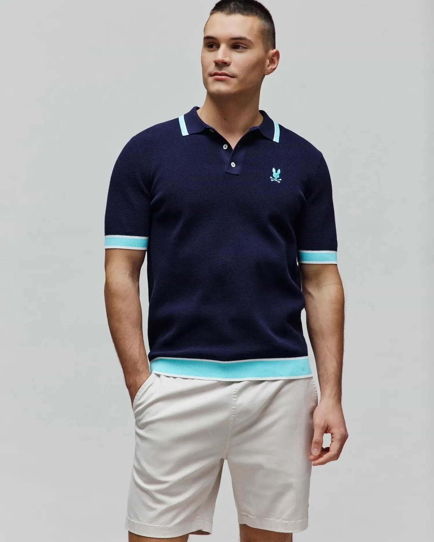 Mens Dax Knit Polo, navy classic fit knit polo with aqua and white striped ribbed collar, cuffs, and hem, featuring a small embroidered aqua Psycho Bunny skull logo on the left chest. (3)