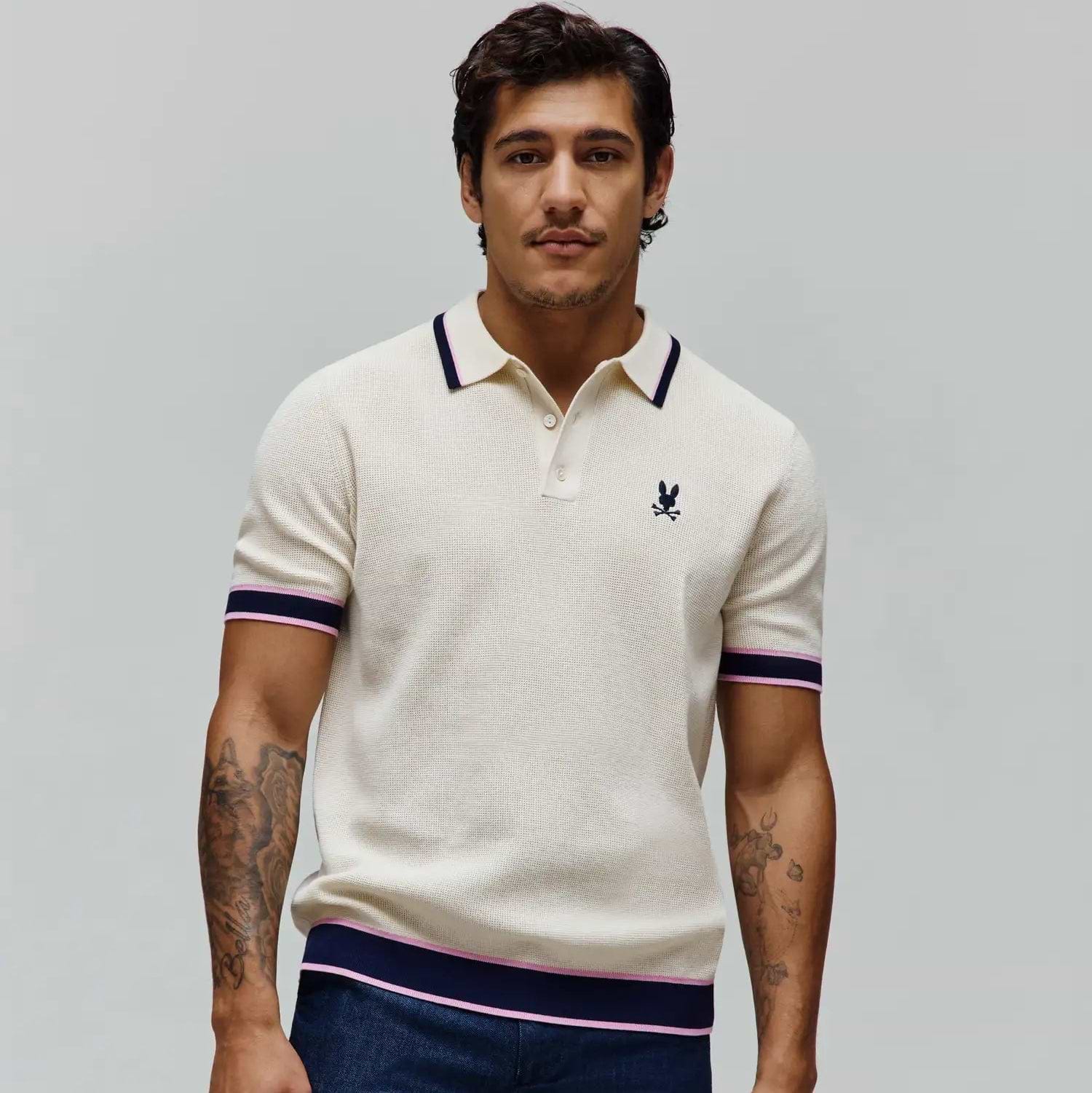 Mens Dax Knit Polo, cream pique knit with classic fit, featuring navy and pink tipped collar, cuffs, and hem, plus a small embroidered navy Psycho Bunny skull logo on the left chest.