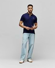 Mens Kenyon Lightweight Pique Polo in navy blue, a classic fit with textured pique fabric. Features a two-button placket, small embroidered Psycho Bunny skull logo on left chest, and red/white stripe accents on collar and cuffs.
