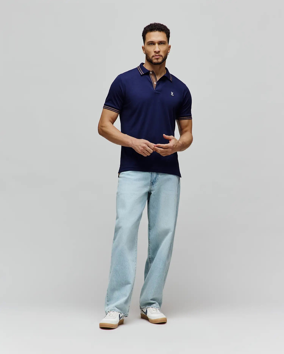 Mens Kenyon Lightweight Pique Polo in navy blue, a classic fit with textured pique fabric. Features a two-button placket, small embroidered Psycho Bunny skull logo on left chest, and red/white stripe accents on collar and cuffs.
