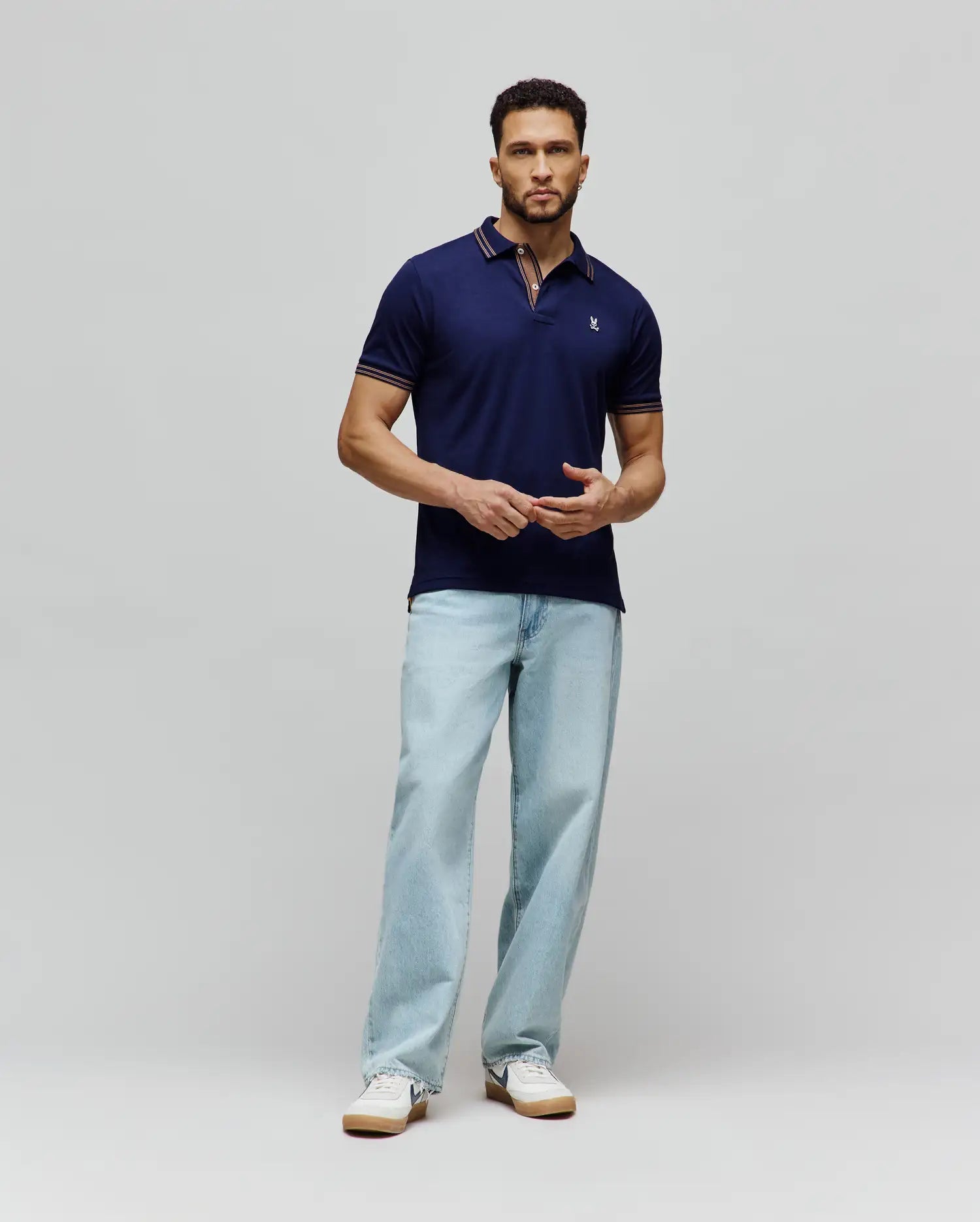 Mens Kenyon Lightweight Pique Polo in navy blue, a classic fit with textured pique fabric. Features a two-button placket, small embroidered Psycho Bunny skull logo on left chest, and red/white stripe accents on collar and cuffs.