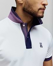 Mens Kenyon Lightweight Pique Polo in white, featuring a classic fit, pique texture, navy collar with purple stripes, matching sleeve cuffs, and a small embroidered Psycho Bunny skull logo on the left chest.