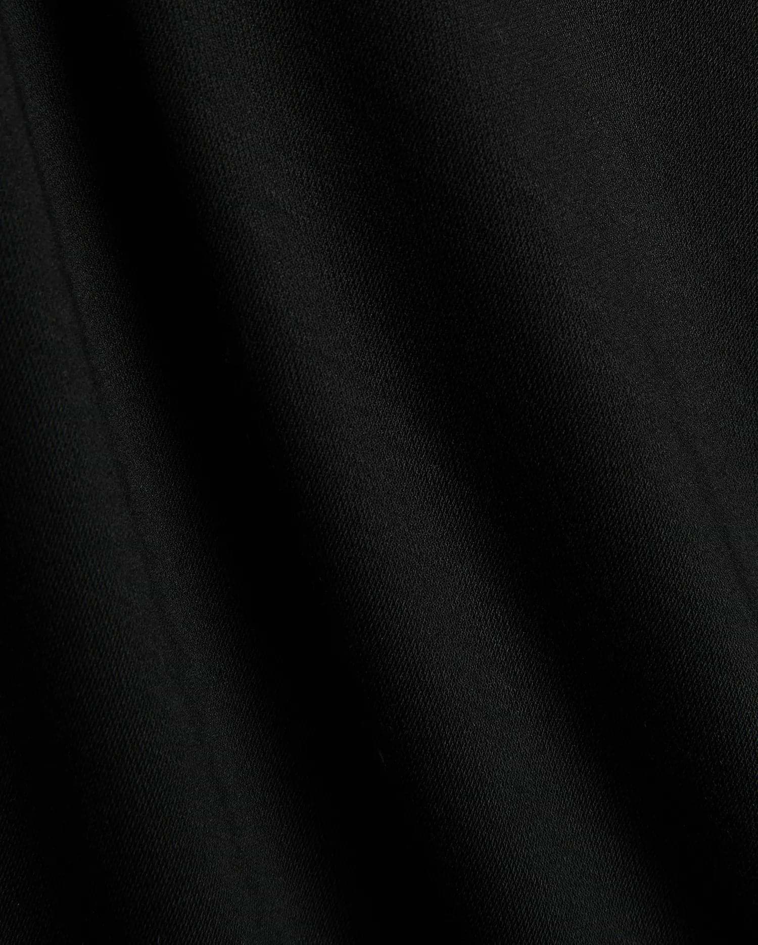 Premium black Mens Timmy Interlock Polo fabric, showcasing a smooth, dense interlock knit with subtle texture and refined drape, embodying Psycho Bunny's sophisticated streetwear style.