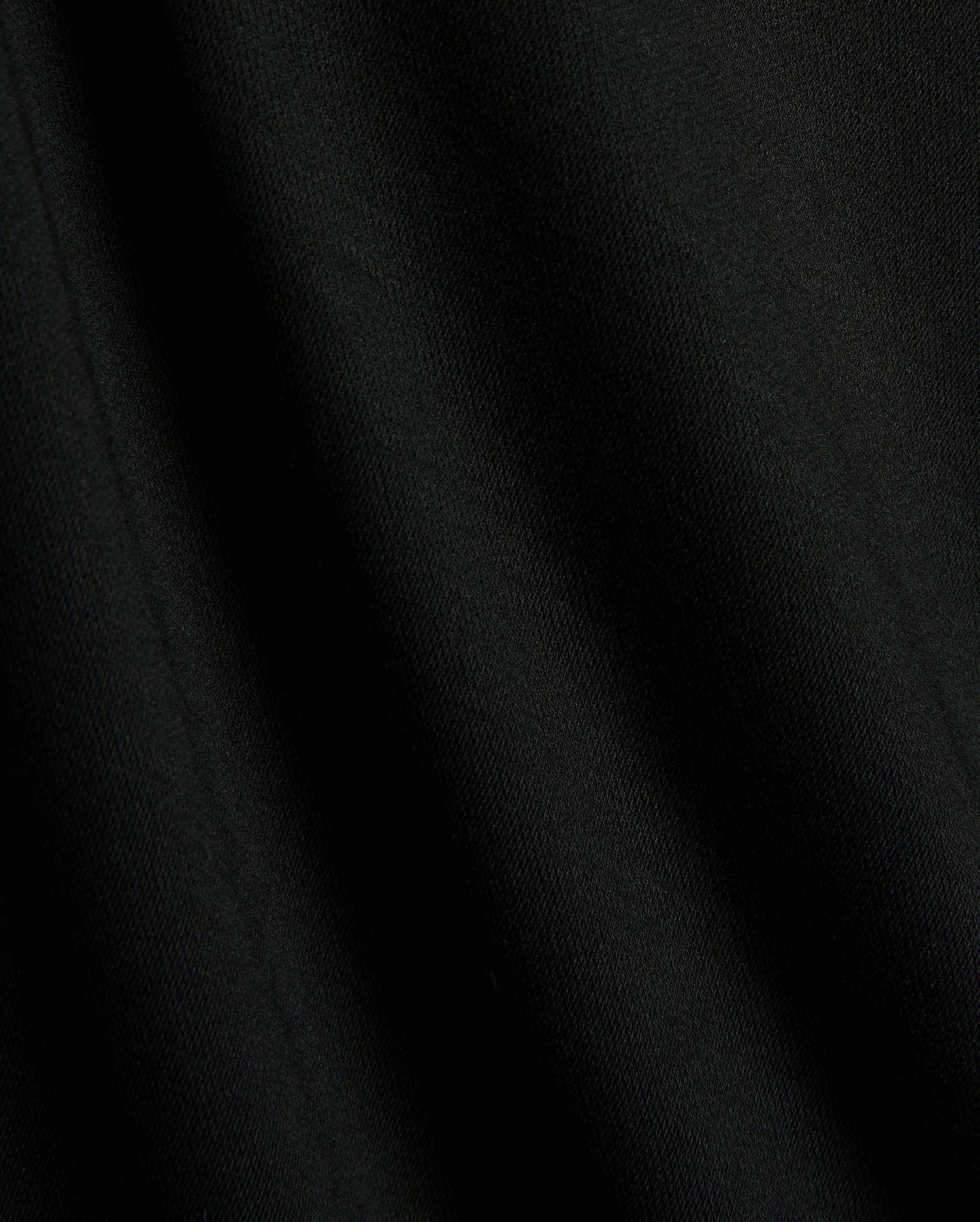 Premium black Mens Timmy Interlock Polo fabric, showcasing a smooth, dense interlock knit with subtle texture and refined drape, embodying Psycho Bunny's sophisticated streetwear style.