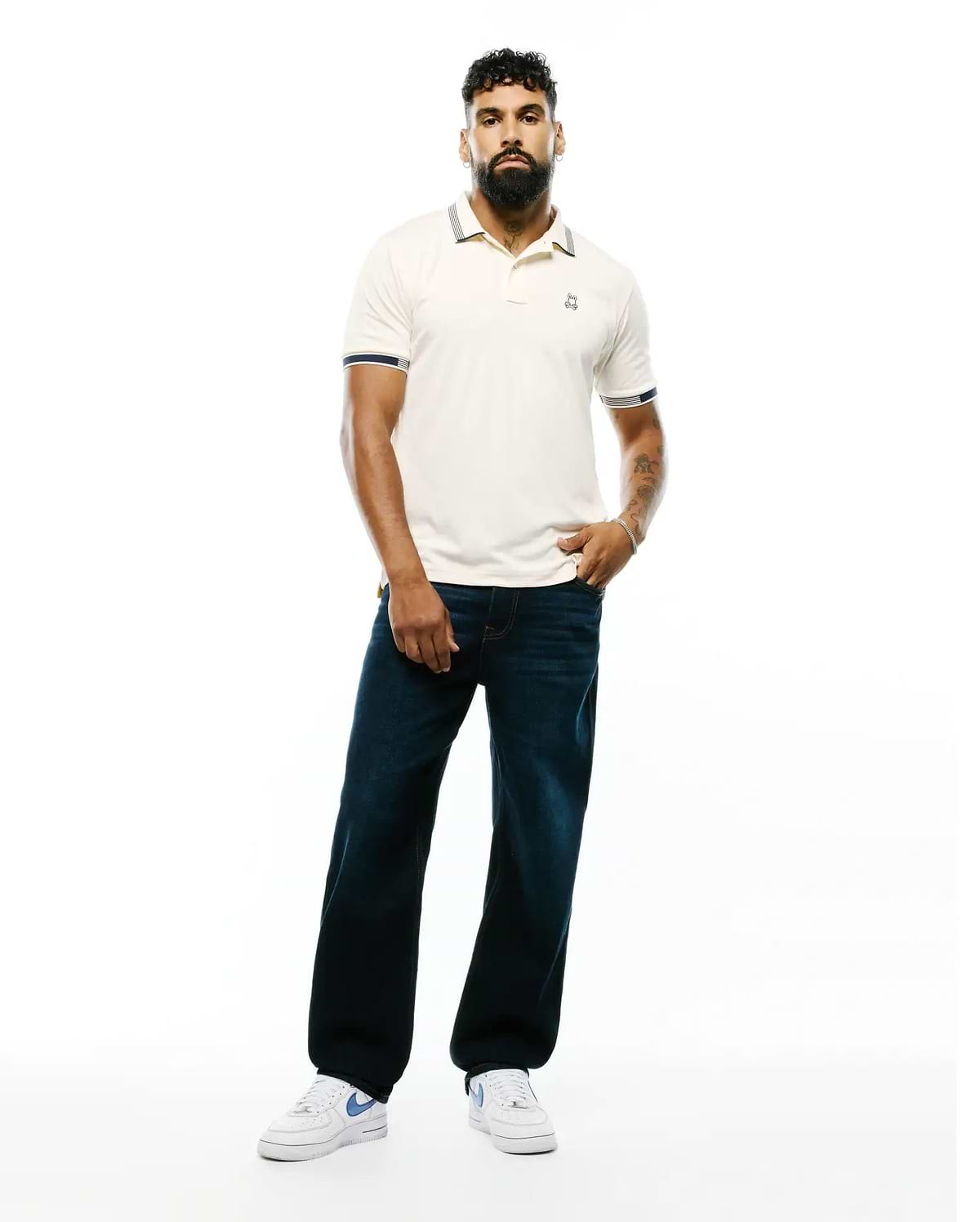 Mens Timmy Interlock Polo, a classic fit cream interlock polo with navy and white striped collar and cuffs, featuring a small embroidered Psycho Bunny skull logo on the left chest.