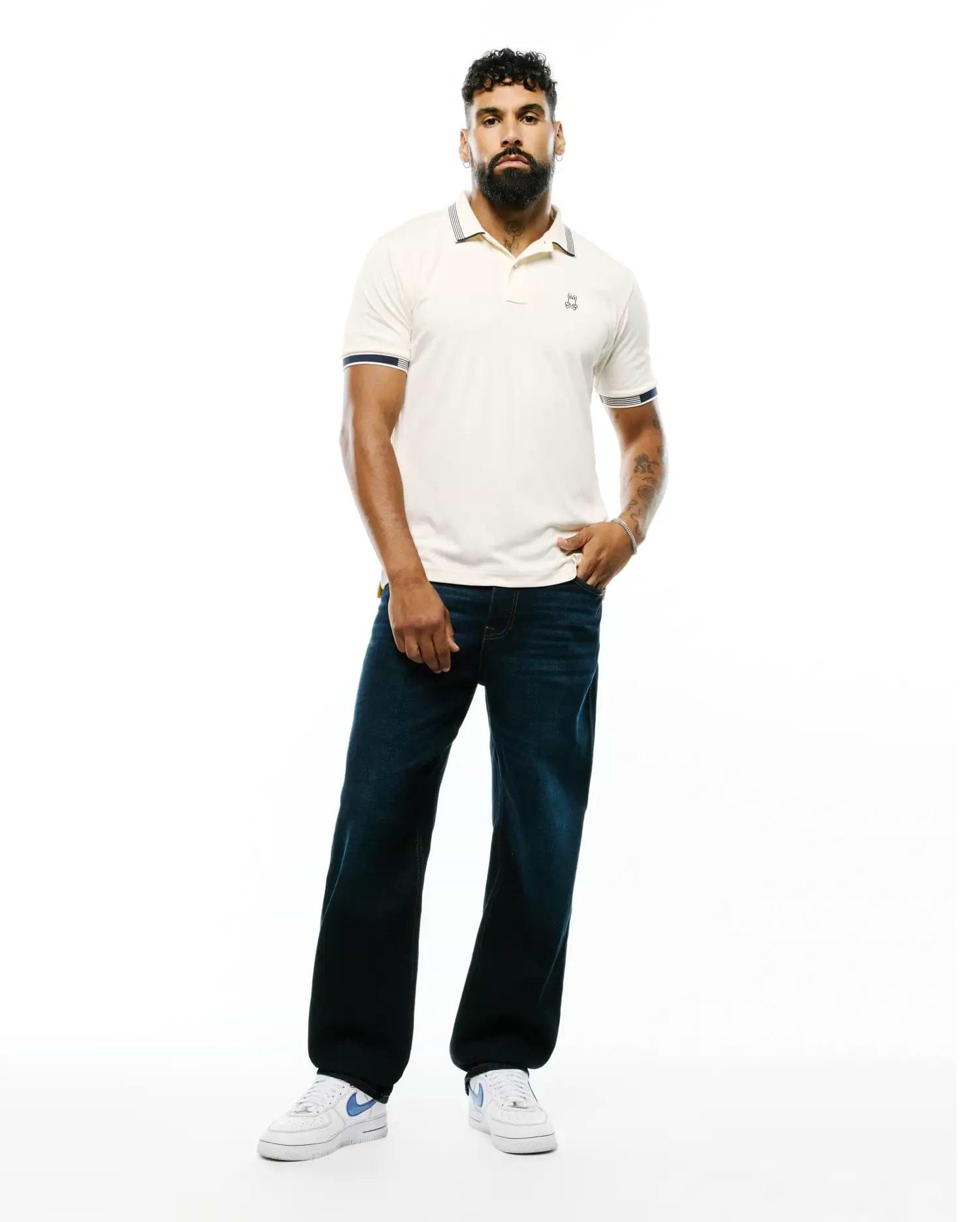 Mens Timmy Interlock Polo, a classic fit cream interlock polo with navy and white striped collar and cuffs, featuring a small embroidered Psycho Bunny skull logo on the left chest.