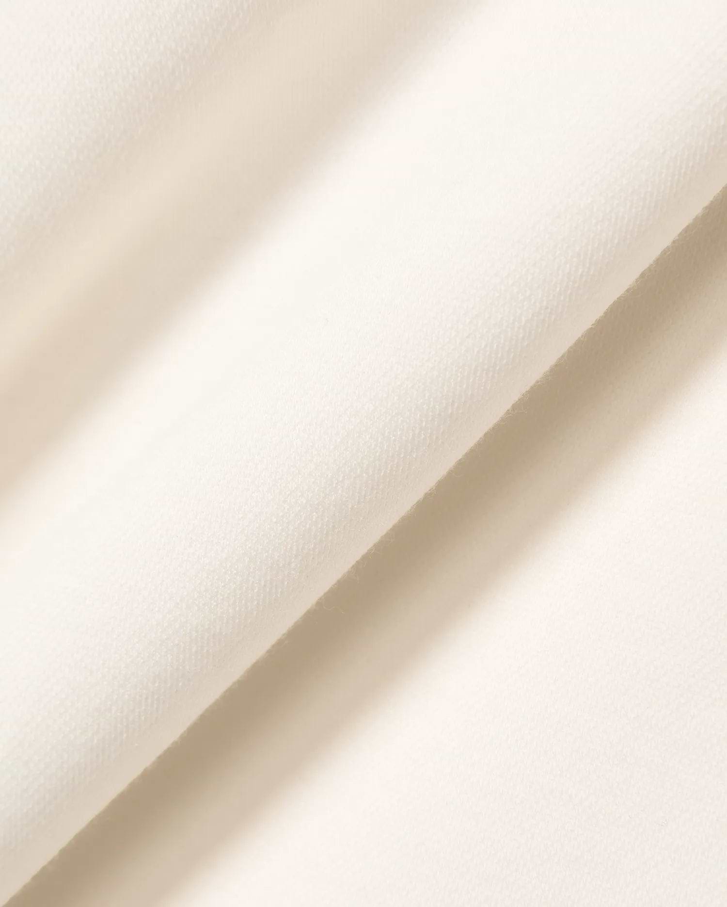 Premium cream Mens Timmy Interlock Polo fabric, featuring a refined, smooth, and dense knit texture, embodying Psycho Bunny's signature bold yet sophisticated streetwear aesthetic.