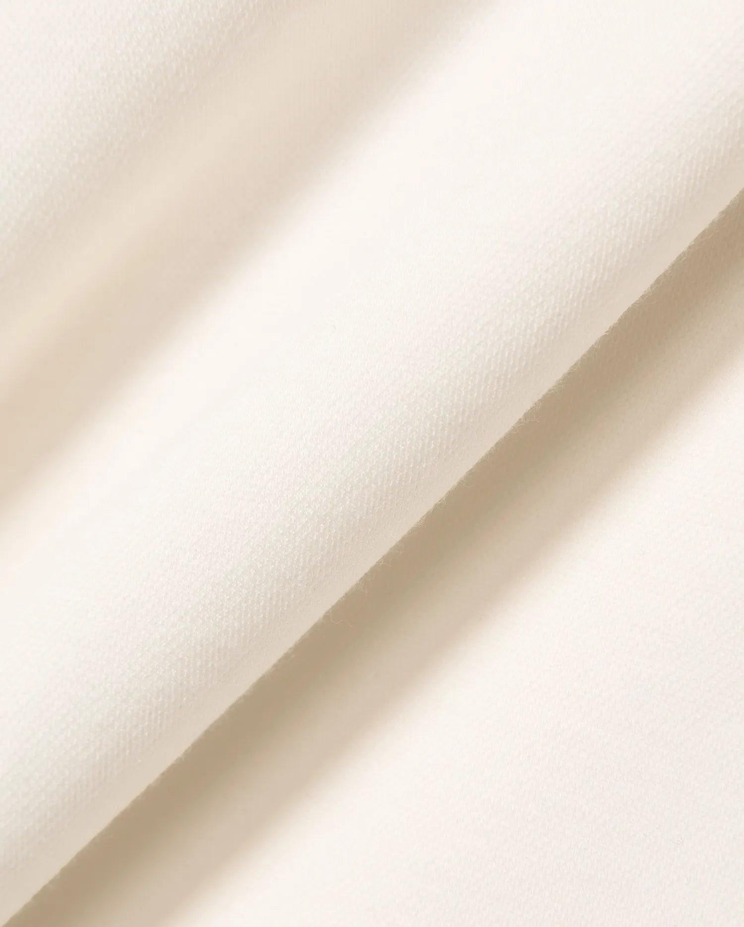 Premium cream Mens Timmy Interlock Polo fabric, featuring a refined, smooth, and dense knit texture, embodying Psycho Bunny's signature bold yet sophisticated streetwear aesthetic.