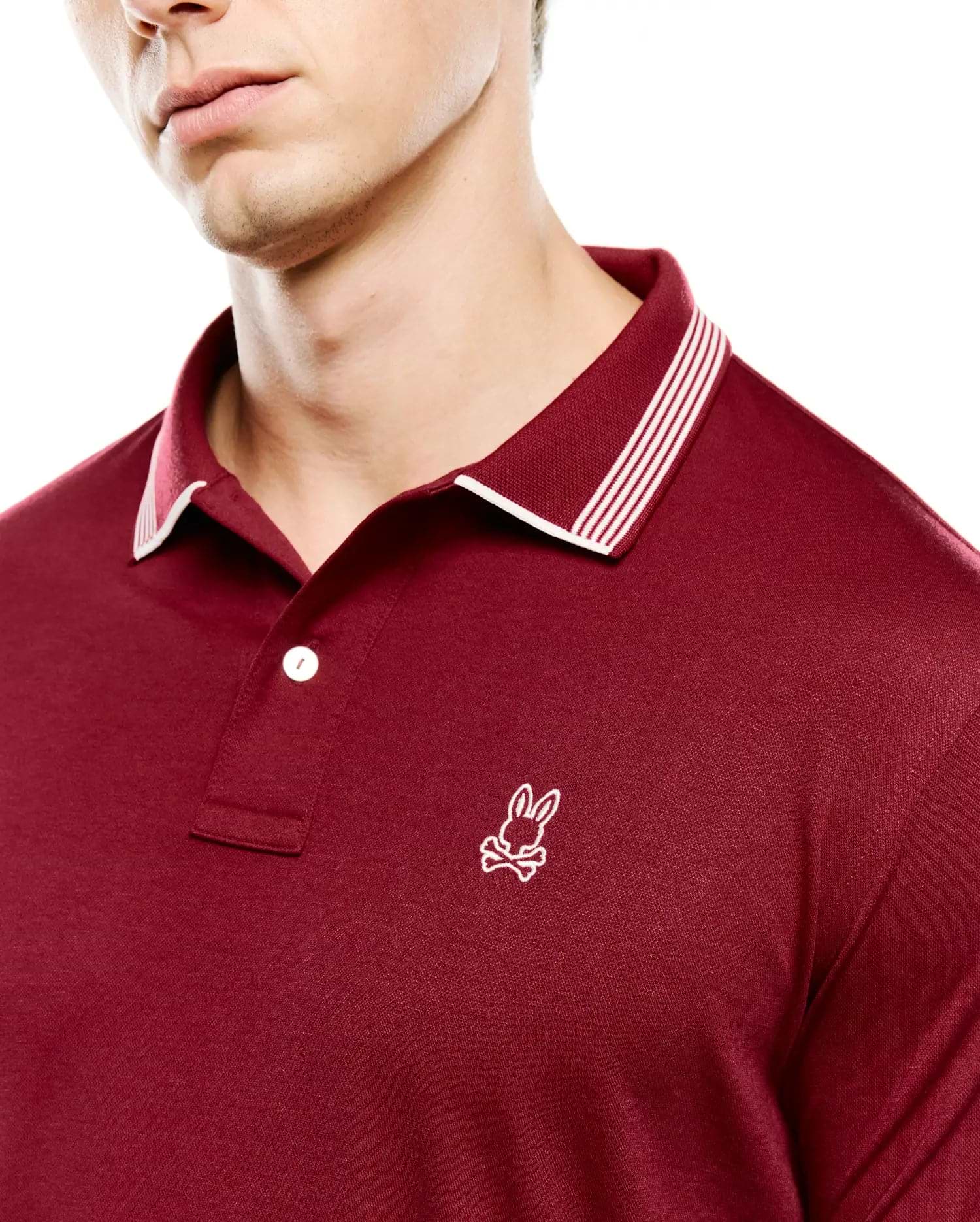 Mens Timmy Interlock Polo in deep maroon, featuring a smooth interlock knit fabric, classic fit, ribbed collar with white tipping and three white stripes, and a small white embroidered Psycho Bunny skull logo on the left chest.