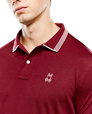 Mens Timmy Interlock Polo in deep maroon, featuring a smooth interlock knit fabric, classic fit, ribbed collar with white tipping and three white stripes, and a small white embroidered Psycho Bunny skull logo on the left chest.