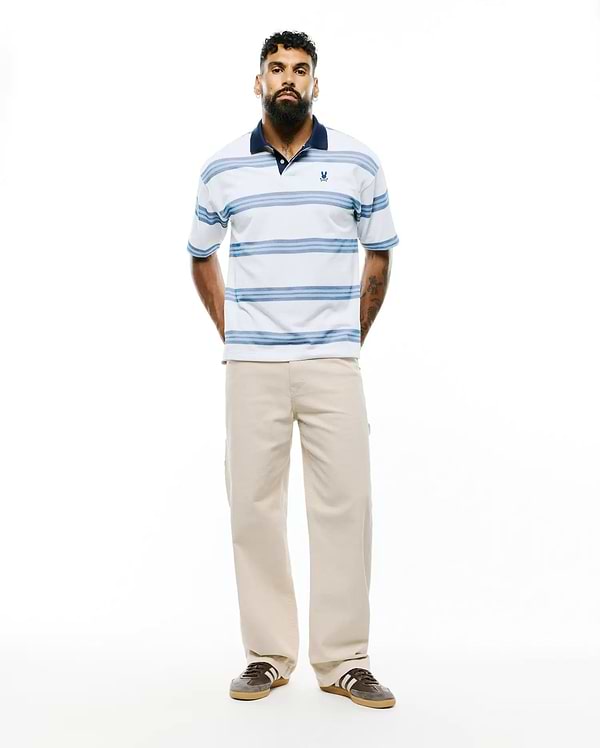 Mens Drew Striped Pique Polo, a classic fit white pique polo with navy collar, light blue horizontal stripes, and a small embroidered Psycho Bunny skull logo on the left chest. (3)