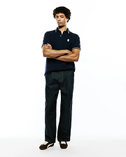 Mens Jaydon Pique Polo in navy blue, featuring a classic fit, textured pique fabric, and a small embroidered white Psycho Bunny skull logo on the left chest, accented with orange and white striped collar and cuffs.