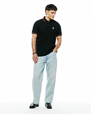 Mens Jaydon Pique Polo, a classic fit black pique polo with a small embroidered white and red Psycho Bunny skull logo on the left chest, featuring red and white striped collar and sleeve cuffs.
