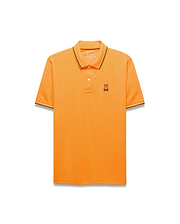 Mens Joji Performance Polo in vibrant orange, featuring a classic fit, smooth jersey fabric, black tipping on the collar and cuffs, and a small embroidered Psycho Bunny skull logo on the left chest.
