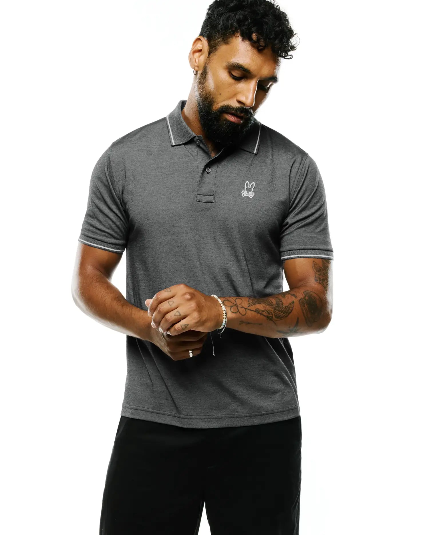 Mens Joji Performance Polo in dark heather grey, featuring a classic fit, white tipped collar and cuffs, and a small embroidered white Psycho Bunny skull logo on the left chest.