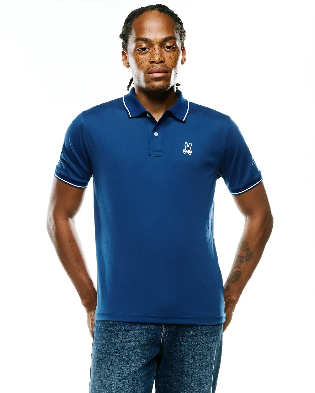 Men's Joji Performance Polo, royal blue classic fit performance jersey polo with white tipped collar and sleeve cuffs, featuring a small white embroidered Psycho Bunny skull logo on the left chest.