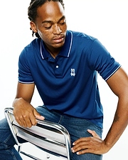 Men's Joji Performance Polo, a classic fit navy blue performance polo with white tipped collar and cuffs, featuring a small embroidered white Psycho Bunny skull logo on the left chest.