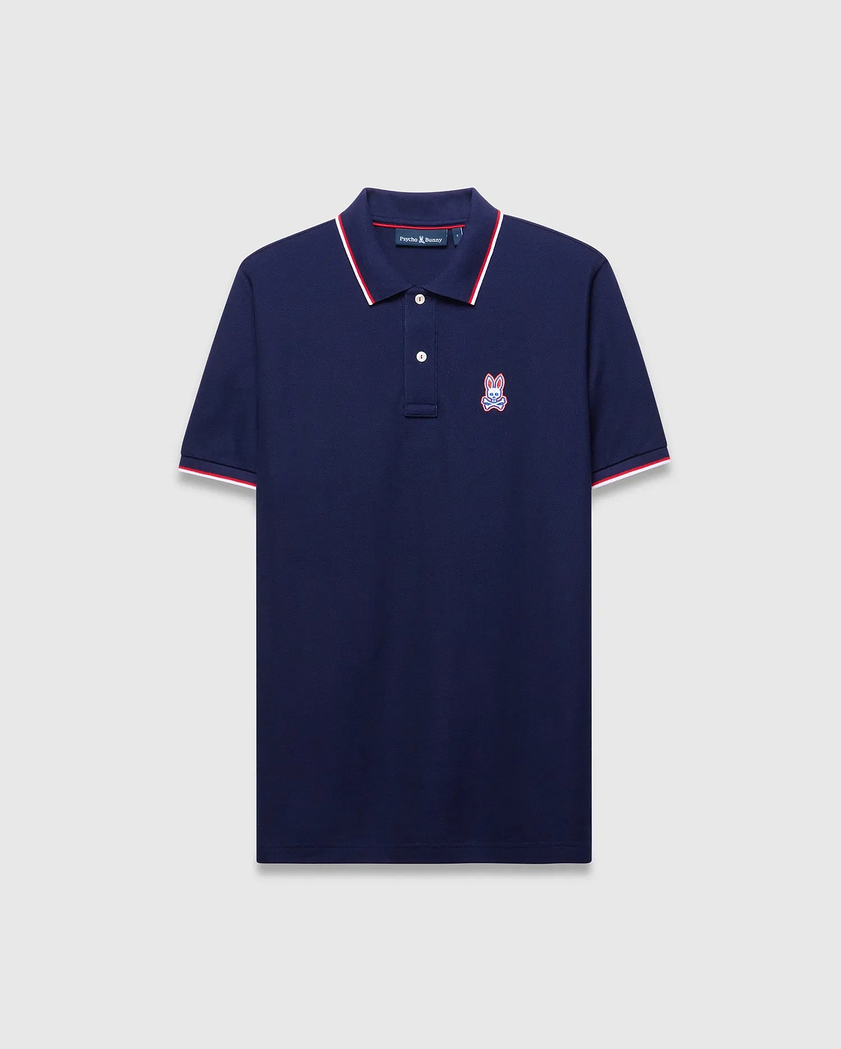 Mens John Pique Polo, a classic fit navy pique polo with red and white tipped ribbed collar and cuffs, featuring an embroidered red, white, and blue Psycho Bunny skull logo on the left chest.