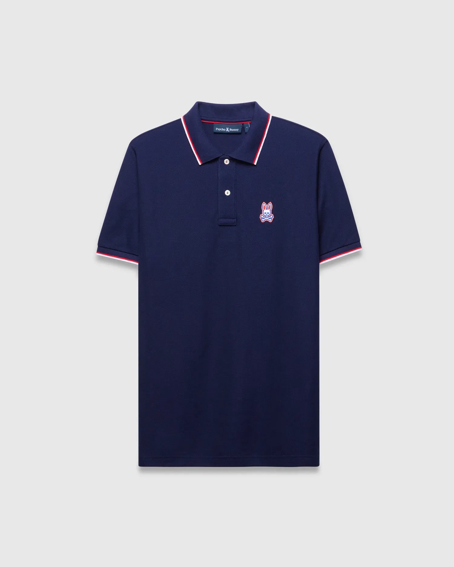 Mens John Pique Polo, a classic fit navy pique polo with red and white tipped ribbed collar and cuffs, featuring an embroidered red, white, and blue Psycho Bunny skull logo on the left chest.