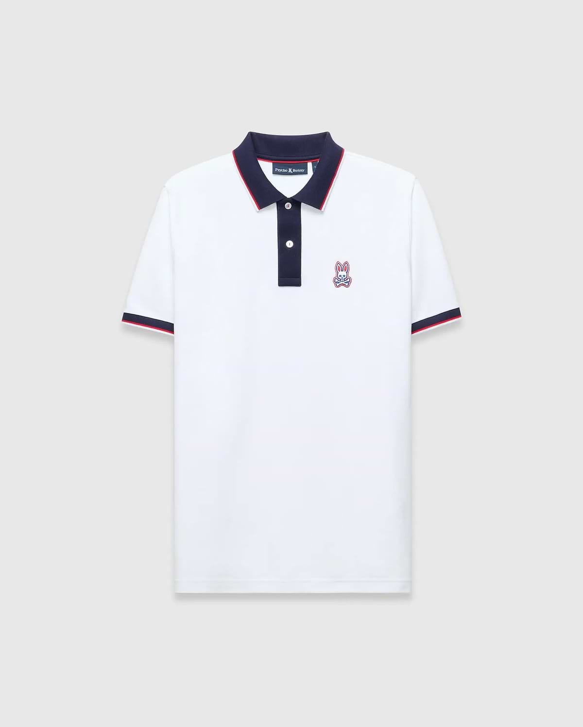 Mens John Pique Polo, a classic fit white pique polo with navy collar and placket, red tipping, navy ribbed cuffs with red stripe, and an embroidered Psycho Bunny skull logo on the left chest.