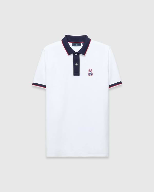 Mens John Pique Polo, a classic fit white pique polo with navy collar and placket, red tipping, navy ribbed cuffs with red stripe, and an embroidered Psycho Bunny skull logo on the left chest.