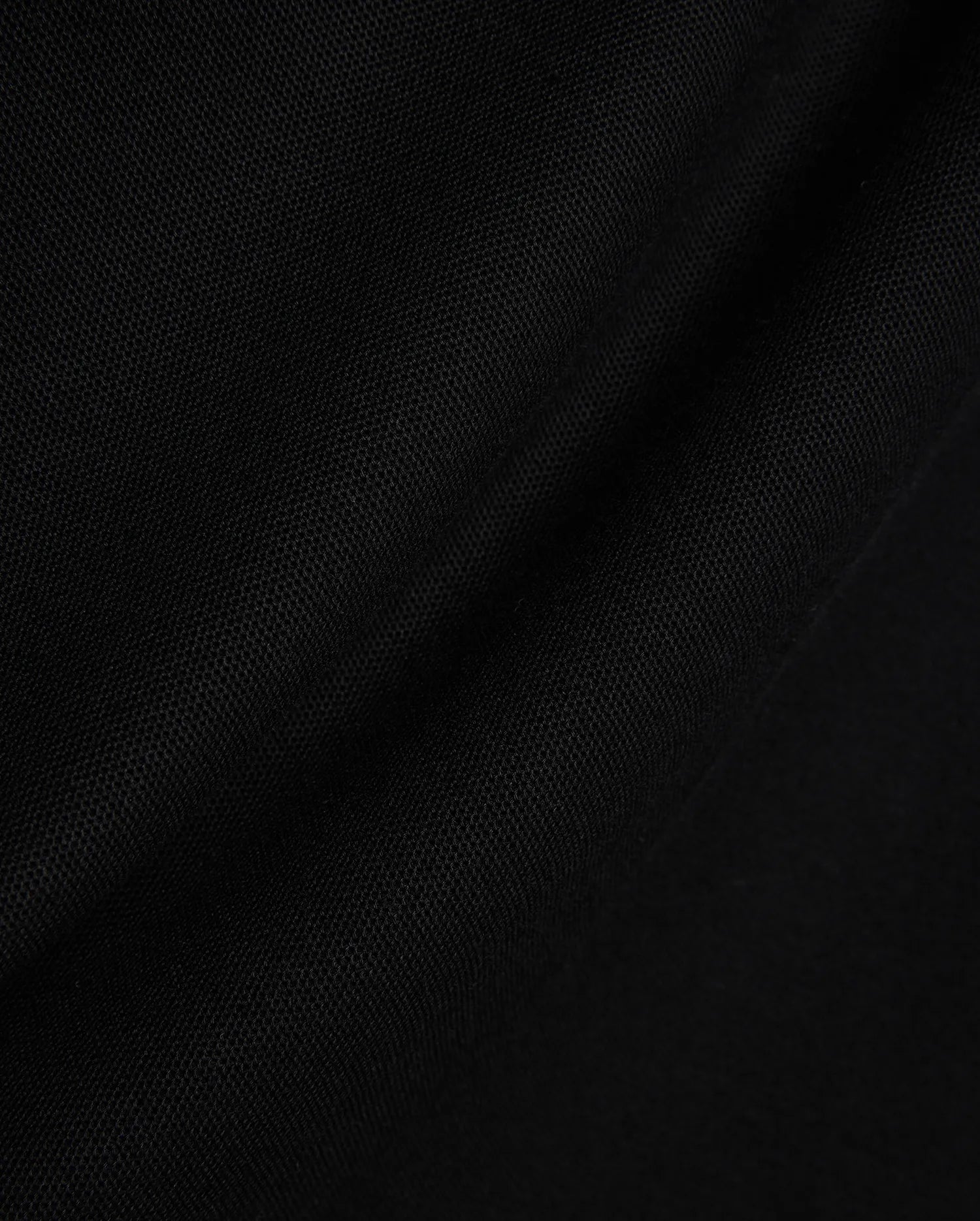 Black Mens Stan Pique Polo fabric, showcasing its premium, finely textured pique weave with subtle, elegant folds, ideal for refined streetwear.