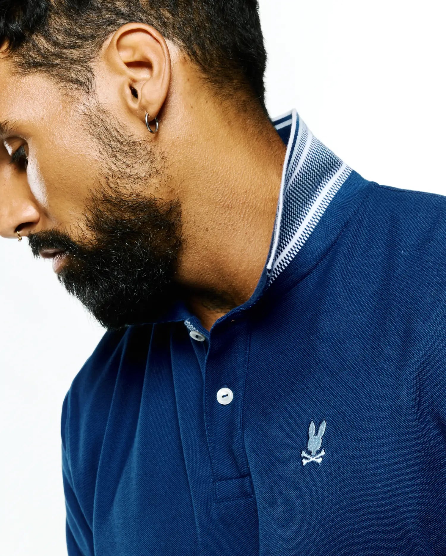 Mens Stan Pima Piqué Polo in deep navy blue, featuring a classic fit, textured piqué fabric, a ribbed collar with white stripes, and a small embroidered Psycho Bunny skull logo on the left chest.