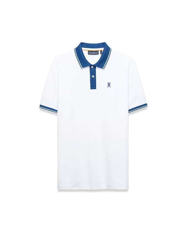 Mens Stan Pima Piqué Polo. White classic fit polo with a contrasting blue collar, two-button placket, and striped sleeve cuffs. Features a small embroidered blue Psycho Bunny skull logo on the left chest.