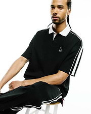 Mens Ceano Relaxed Fit Heavy Pique Polo in black with a white collar, white double stripes on sleeves, small embroidered white bunny skull logo on left chest, and side vents with a pink accent.