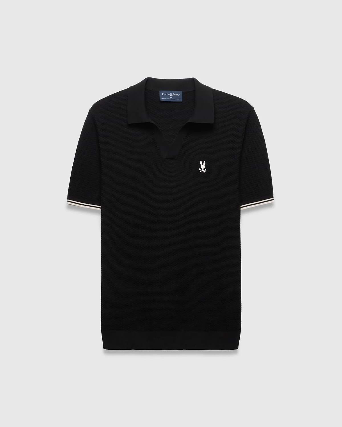 Black Mens Selby Knit Polo featuring a textured knit, classic fit, v-neck collar, and ribbed cuffs with white and cream double stripes. A small white embroidered Psycho Bunny skull logo adorns the left chest. (4)