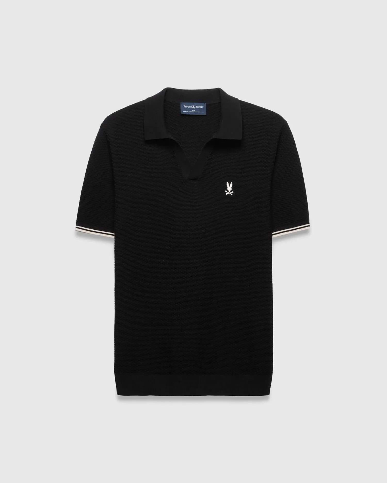 Black Mens Selby Knit Polo featuring a textured knit, classic fit, v-neck collar, and ribbed cuffs with white and cream double stripes. A small white embroidered Psycho Bunny skull logo adorns the left chest. (4)