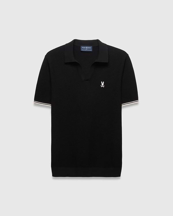 Black Mens Selby Knit Polo featuring a textured knit, classic fit, v-neck collar, and ribbed cuffs with white and cream double stripes. A small white embroidered Psycho Bunny skull logo adorns the left chest. (4)
