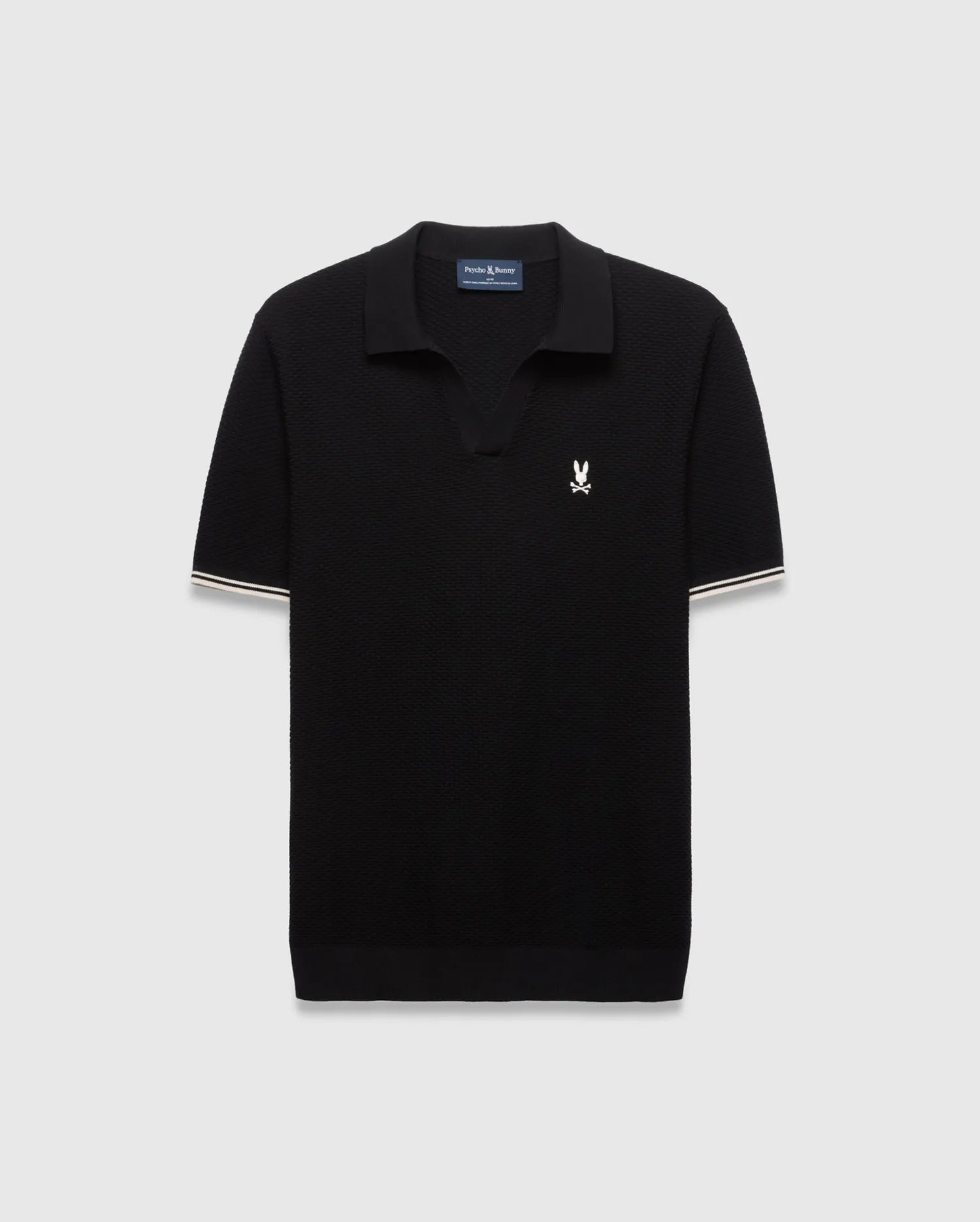 Black Mens Selby Knit Polo featuring a textured knit, classic fit, v-neck collar, and ribbed cuffs with white and cream double stripes. A small white embroidered Psycho Bunny skull logo adorns the left chest. (4)