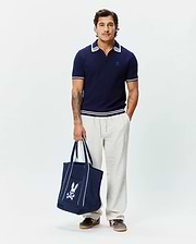 Mens Elowen Knit Polo, navy ribbed knit with a classic fit, featuring a white double-striped collar and cuffs, and a small embroidered Psycho Bunny skull logo on the left chest.