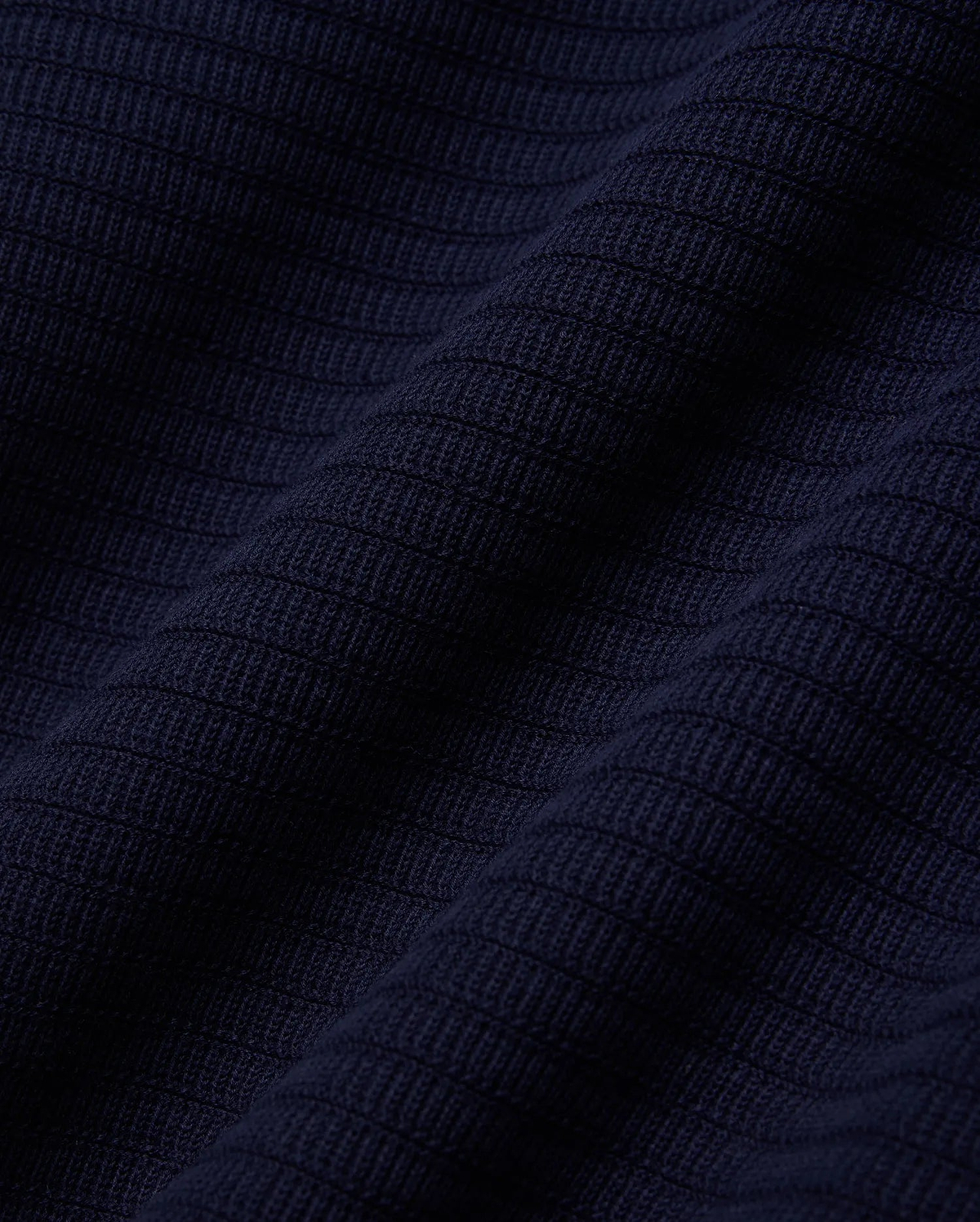 MENS ELOWEN KNIT POLO in deep navy blue, showcasing a finely crafted, horizontally ribbed knit texture with a soft, luxurious feel, characteristic of premium Psycho Bunny apparel.
